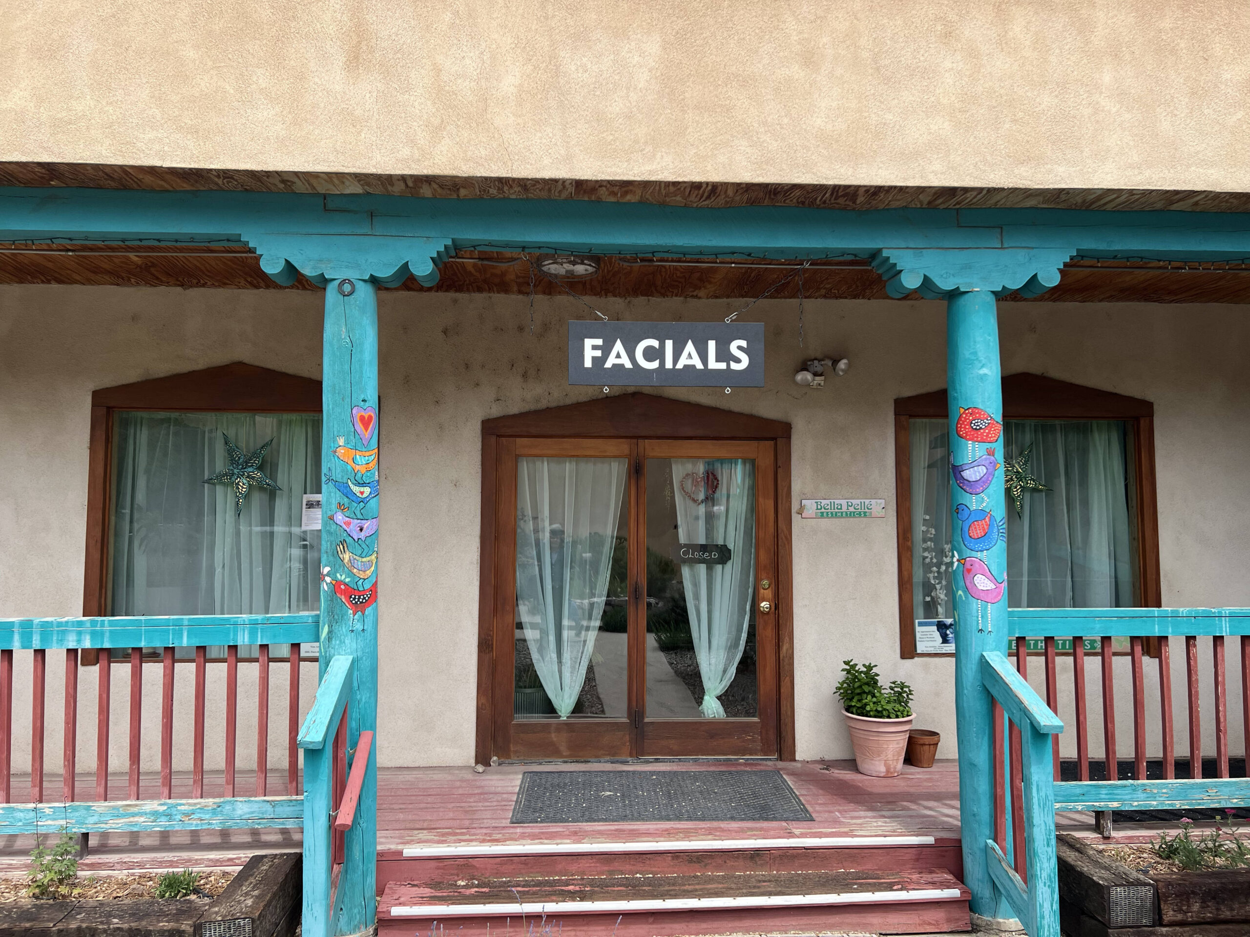 Steps and ralings leading up to a porch and glass door entrance under a sign that says facials